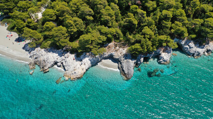 Aerial drone photo of secluded rocky cove near turquoise pebble paradise beach of Kastani covered with pine trees, Skopelos island, Sporades, Greece
