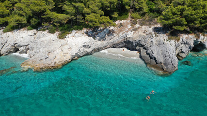 Aerial drone photo of secluded rocky cove near turquoise pebble paradise beach of Kastani covered with pine trees, Skopelos island, Sporades, Greece