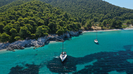 Aerial drone photo of secluded rocky cove near turquoise pebble paradise beach of Kastani covered with pine trees, Skopelos island, Sporades, Greece