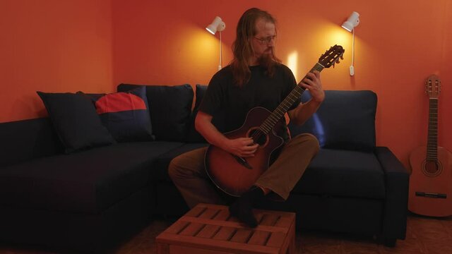 Man practicing guitar playing at home