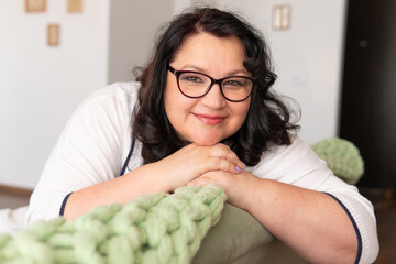 Portrait of a fat woman sitting on a sofa in an apartment