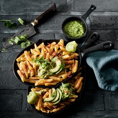 Two skillets with French fries and guacamole