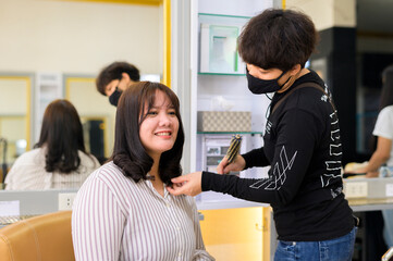 hairdresser giving a new haircut to Asia women customer at salon,Beautiful cute young plus size female with loose dark hair enjoying