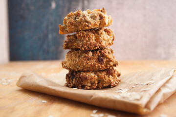 Homemade oatmeal cookies folded in a pile on baking paper. Wooden background
