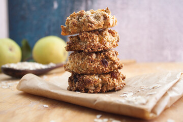 Homemade oatmeal cookies folded in a pile on piece of sackcloth with pears behind. Wooden background
