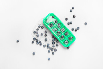 Tray with berries in ice on light background