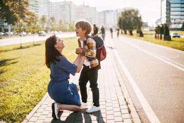 Mom hugs her naughty son on the way to school, mom and boy say goodbye before school. Concept of...