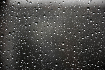 Raindrops on the window pane slowly flowing down