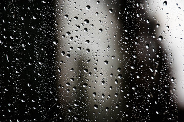 Raindrops on the window pane slowly flowing down