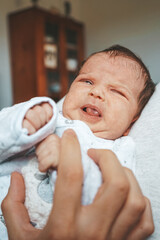 Upset newborn baby in pajama at home