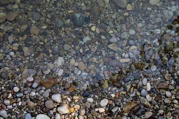 Texture of river pebbles half under water.