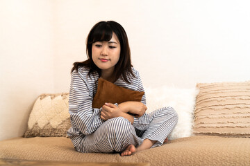 Fototapeta premium パジャマ姿でソファーに座る若い主婦