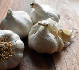 Spanish Garlic bulbs and cloves on wooden chopping board under natural light.