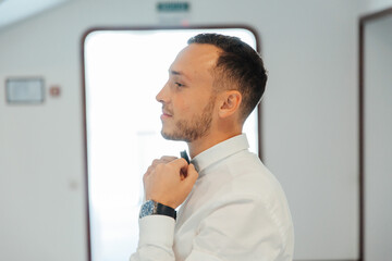 Portraits of the groom at the hotel training camp, dressed as a businessman in a black suit, tuxedo and white shirt