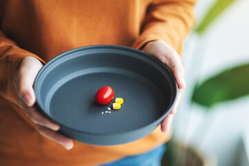 Closeup image of a woman holding a plate of small amount of food for diet concept