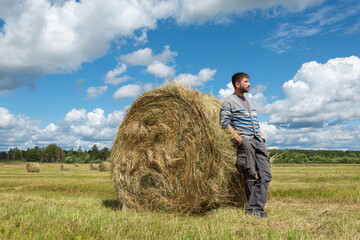 Naklejka na ściany i meble Handsome young man standing by a haystack.