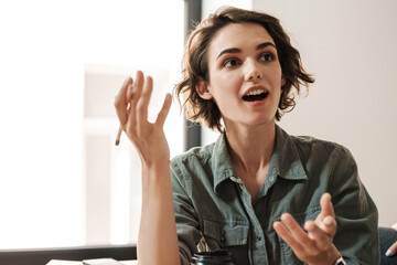 Image of amazed beautiful woman discussing project while working