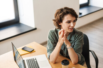 Image of young woman discussing project while working with laptop