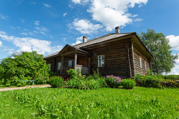 Fototapeta na wymiar Old wooden Russian house on the green lawn in summer. Horizontal image.