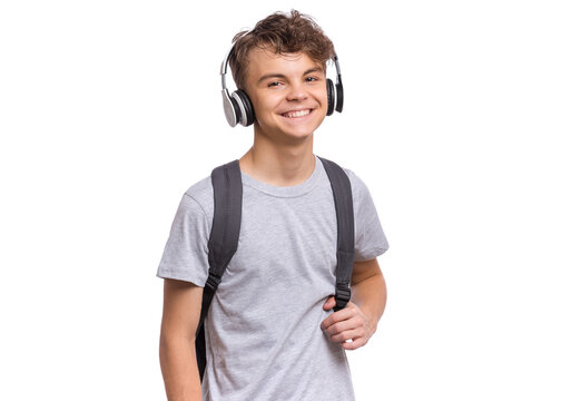 Happy teen boy with headphones and backpack, isolated on white background. Cheerful child listening to music and looking at camera. Emotional portrait of handsome teenager guy Back to school.