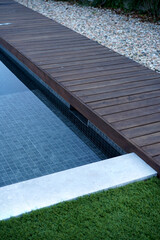 Blue swimming pool with wooden deck                       