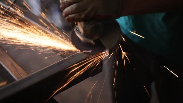 Grinding metal with a grinder. Metal profile corners processing. Work with an electric tool. A worker is grinding metal. Lots of friction sparks.
