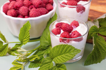 Dessert of fresh raspberries and cream. Ripe berries with leaves on the table.
