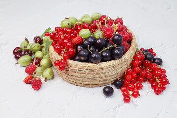 Bright variety of berries lie in a wicker basket on a white background. A mix of vitamins from summer healthy food.