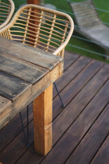 Close up shots of a wooden rustic table standing on a deck with the swimming pool in the background and green fake grass     