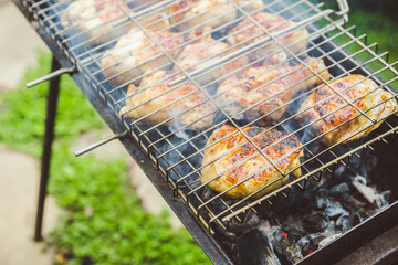 Chicken legs grilling on the brazier. Selective focus.