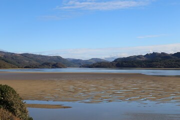 An exposed sand bar in the Mawddach Estuary looking upstream towards the mountains of Snowdonia, Wales.