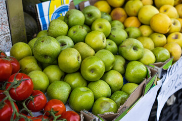 Manzanas verdes expuestas al aire libre en una frutería con luz de día a la sombra