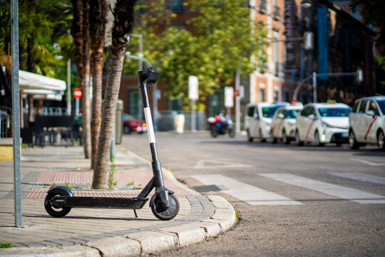 Patinete el&eacute;ctrico de alquiler aparcado cerca de un paso de peatones en una parada de taxi