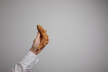 Close-Up of woman holding ripe yellow banana against white background.