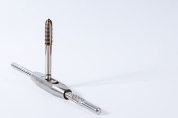 Manual tap for cutting threads in metal on a white background. Metal processing tool. Copy space.