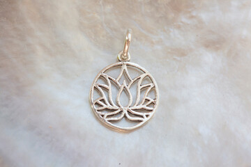 Silver pendant in the shape of lotus on white shell background