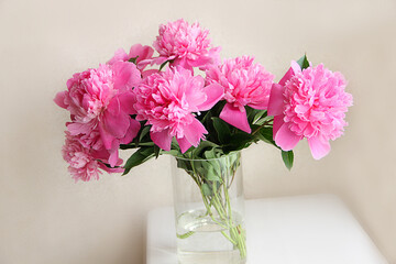 bouquet of pink peonies in a vase on a wooden table