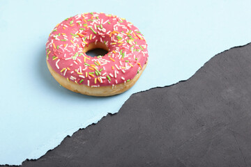 Donut ring on torn pastel paper background.