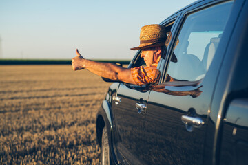 Young man in straw hat driving truck. Life on a farm. 