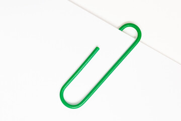 Obraz premium Green paper clip on white paper 