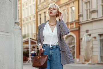 Street fashion photo of elegant  woman wearing trendy white blouse, stylish checkered blazer, high...
