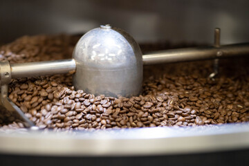 freshly roasted coffee is cooled in a cooler drum. the roaster's blades interfere with the coffee....