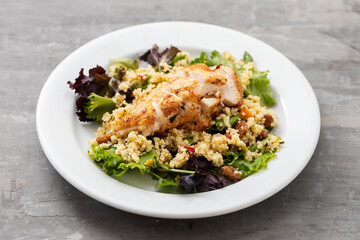 chicken with vegetables and quinoa on dish on ceramic background