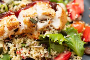 chicken with vegetables and quinoa on dish on ceramic background