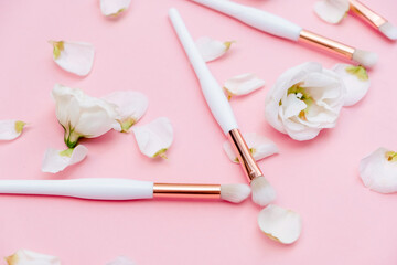 Makeup brushes and flowerss on white background. Top Horizontal view copyspace.