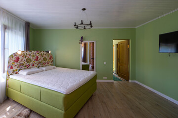 Contemporary interior of luxury bedroom. Cozy bed with pillows. Green walls.