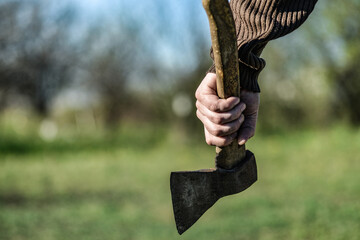 An angry and dangerous man holds an ax in his hand and is about to commit a crime. Lumberjack with an ax in his hand.