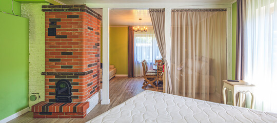 Modern interior of luxury bedroom in private house. Huge bed. Brick fireplace. Set table. Green walls.