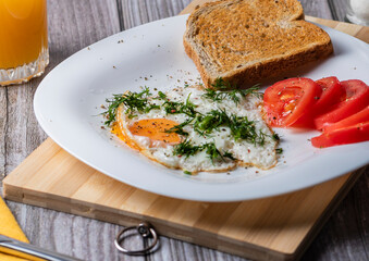 Fried eggs on a platter served with parsley and tomatoes.