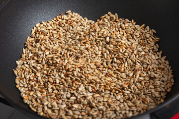 Fried sunflower seeds in a frying pan, peeled.